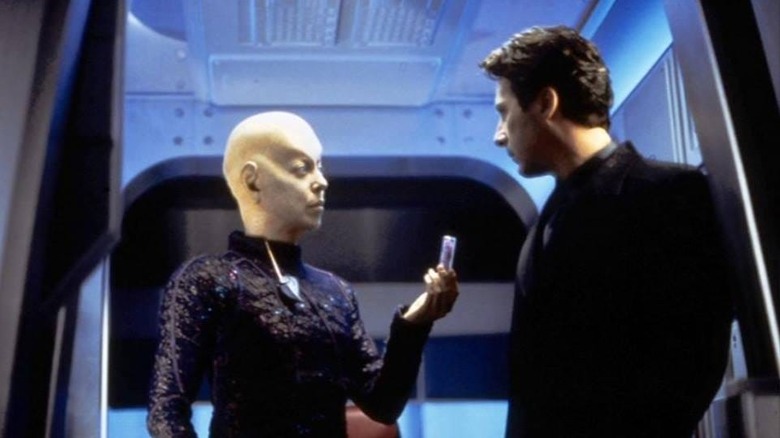 A big-headed alien handing a vial of something to a human, a scene from Earth: Final Conflict.