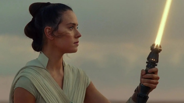 Rey holds up her lightsaber in Star Wars: The Rise of Skywalker