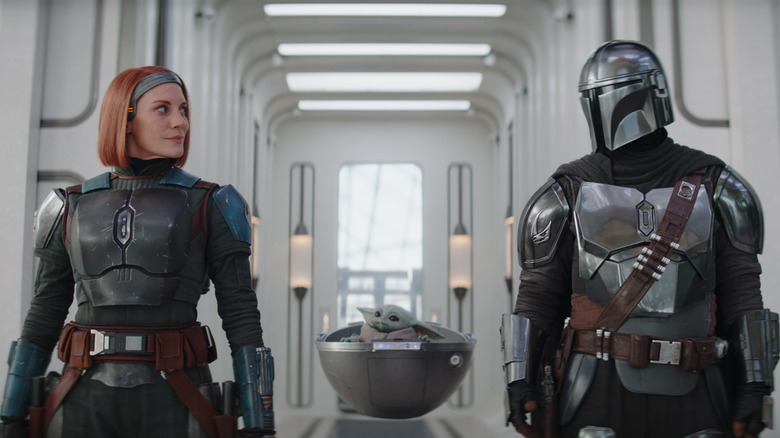 Bo-Katan walking by Din Djarin with Grogu behind them in The Mandalorian season 3