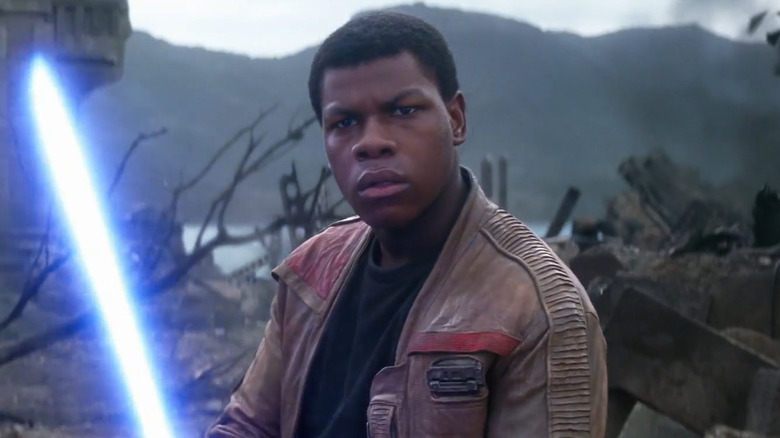 John Boyega as Finn holding a lightsaber in Star Wars: The Force Awakens