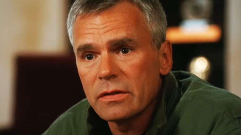 Richard Dean Anderson's Jack O'Neill is seen in closeup as he sits in a meeting room in Stargate SG-1