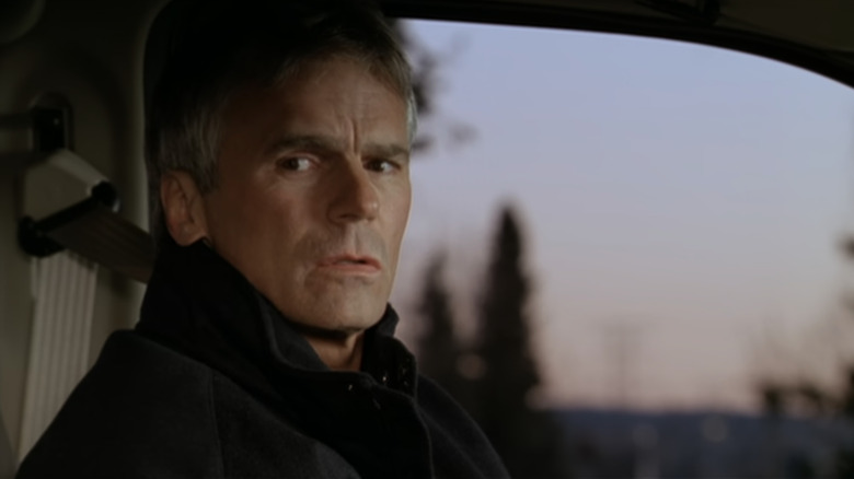 Richard Dean Anderson's Jack O'Neill sits in a car looking off to his right in Stargate SG-1