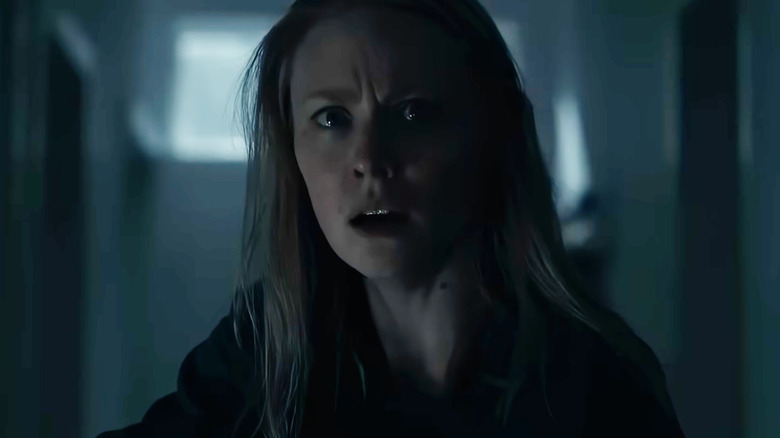 Deborah Ann Woll as Meg looking alarmed in a dark hallway in The Cycle