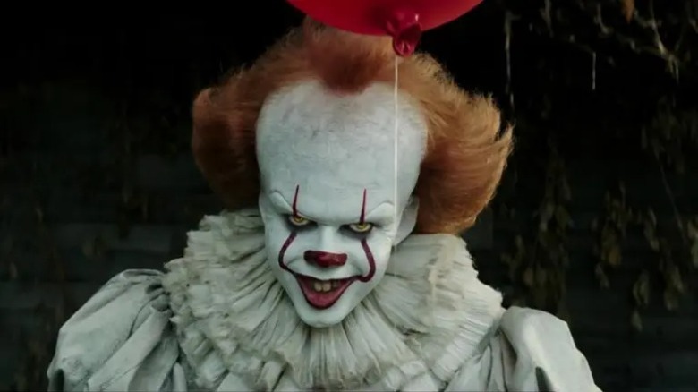 Pennywise smiles, holds balloon
