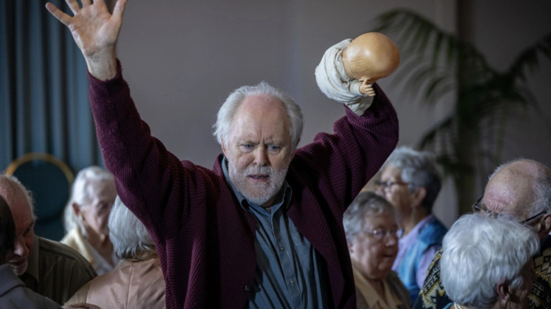 Dave with his hands up, a doll in one of them, in The Rule of Jenny Pen