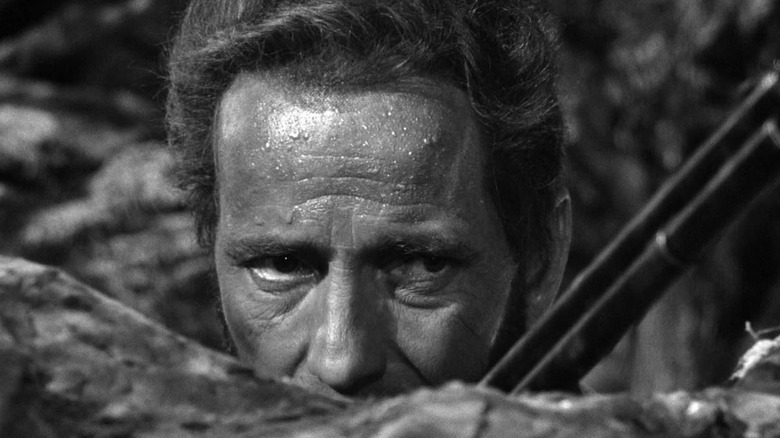 Fred Dobbs, sweaty, peeking over a rock in The Treasure of the Sierra Madre