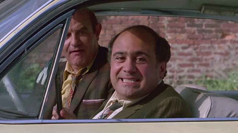 Danny DeVito as Ernest Tilley grinning while holding a crowbar in Tin Men