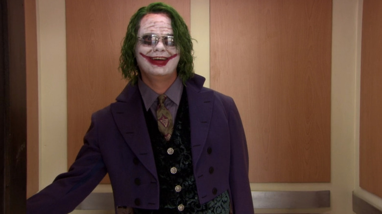 Rainn Wilson as Dwight Schrute stands in an elevator dressed as The Joker in The Office