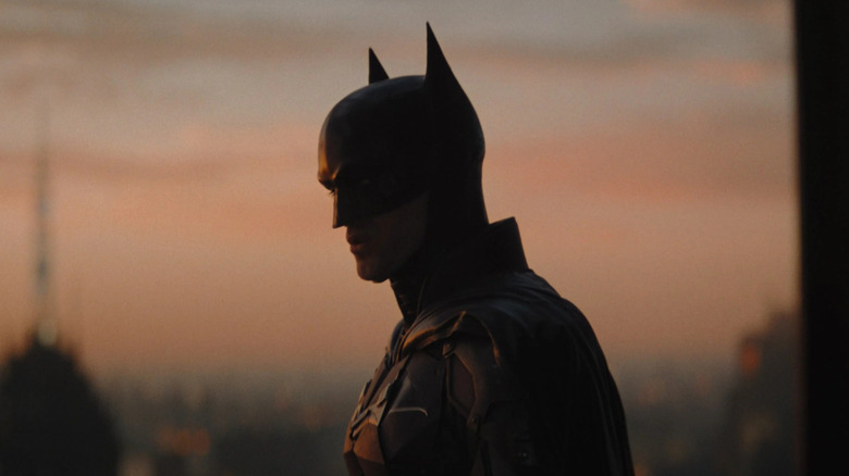 The Batman standing against a dusky sky in The Batman