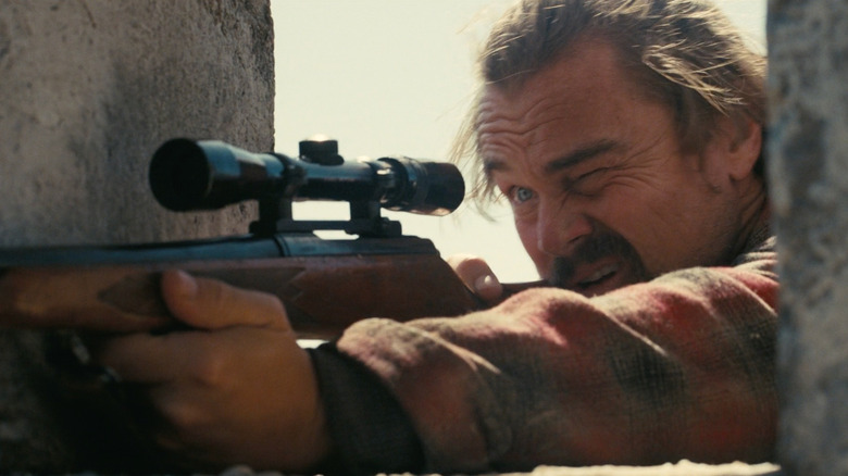 Leonardo DiCaprio as Bob looking through the scope of a rifle in One Battle After Another