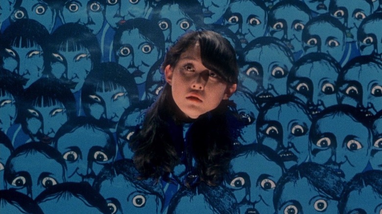 Gorgeous' floating head among a head mural in House