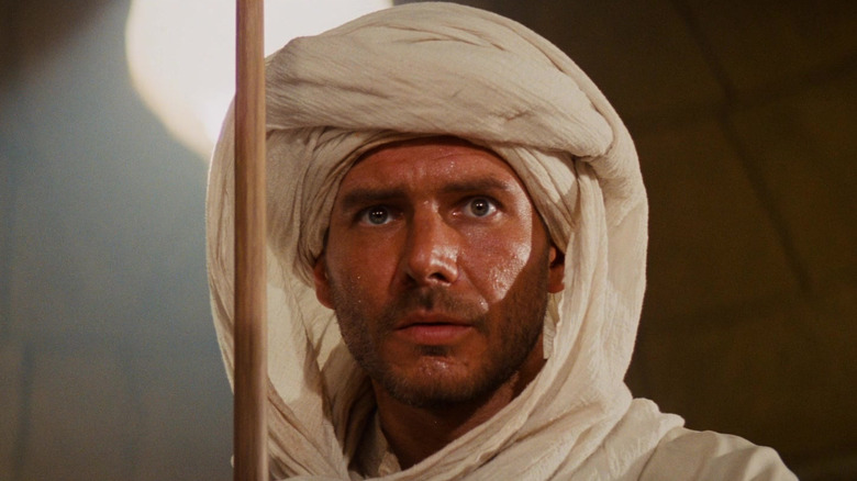 Indiana Jones holding a staff in an underground chamber in Raiders of the Lost Ark
