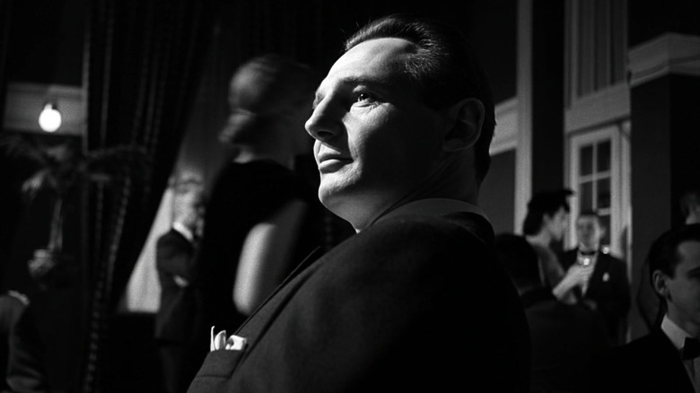Oskar Schindler smiling while sitting down in Schindler's List
