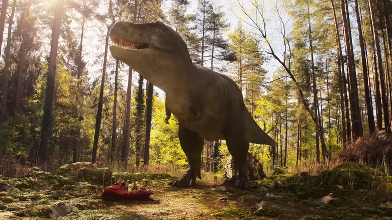 A Tyranosaurus Rex stands over its prey in a forest in The Dinosaurs