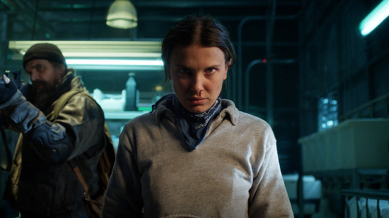 Eleven (Millie Bobby Brown) stares intensely with Jim Hopper (David Harbour) behind her in Stranger Things