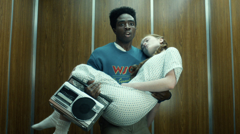 Lucas Sinclair (Caleb McLaughlin) holds an unconscious Max Mayfield (Sadie Sink) and a boombox in an elevator in Stranger Things