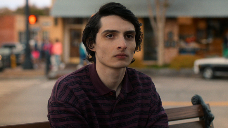 Mike Wheeler (Finn Wolfhard) sits sullenly on a bench in town in Stranger Things