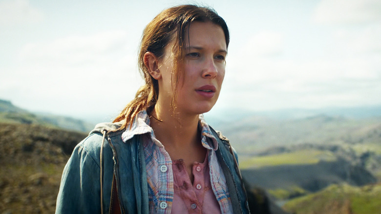 Milly Bobby Brown's Eleven looks off into the distance as she walks in mountainous terrain in Stranger Things