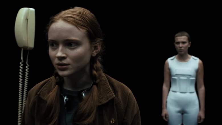 Max (Sadie Sink) stood by a phone in the void with Eleven (Millie Bobby Brown) stood behind her in Stranger Things