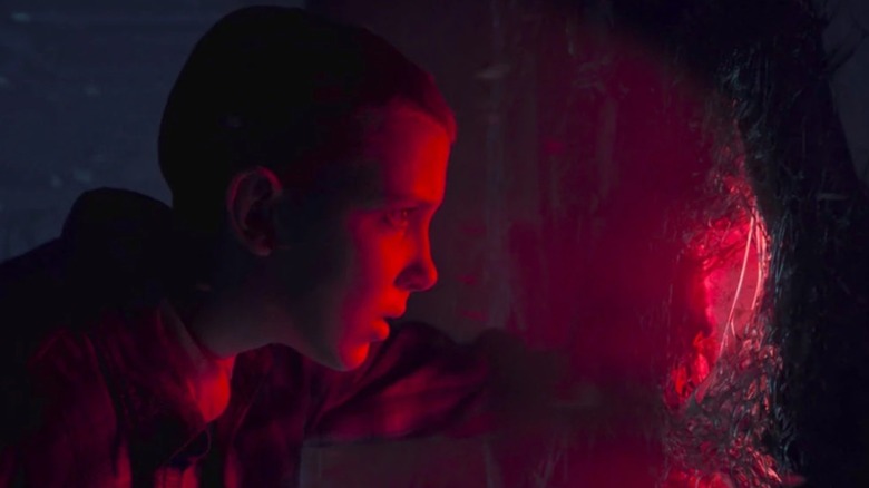 Eleven (Millie Bobby Brown) sticking her hand through a rift in Stranger Things