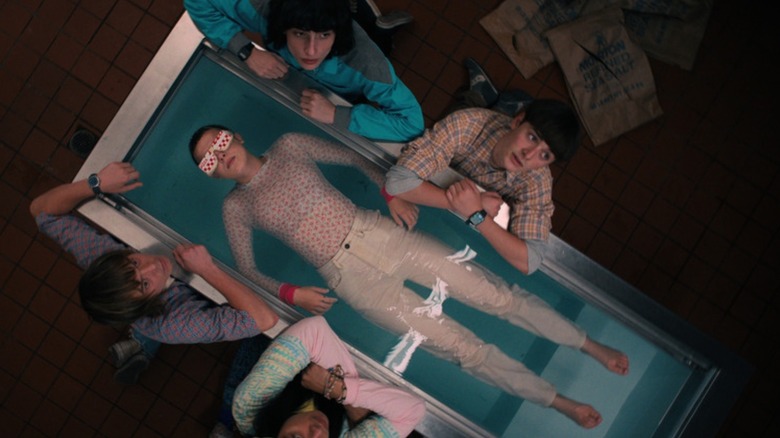 Eleven (Millie Bobby Brown) floating in a pool of water surrounded by Mike Wheeler (Finn Wolfhard), Will Byers (Noah Schnapp), Jonathan (Charlie Heaton) and Argyle (Eduardo Franco) in Stranger Things