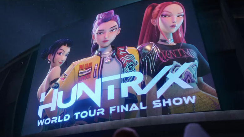 Zoey, Rumi, and Mira appear on a big screen billboard in KPop Demon Hunters