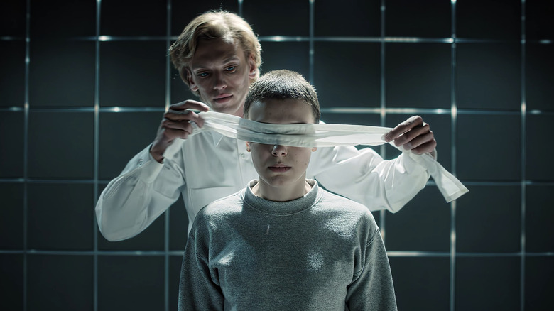 Jamie Campbell Bower's Henry Creel puts a blindfold on Milly Bobby Brown's Eleven in Stranger Things