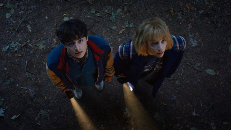 Will and Robin holding flashlights and looking up at night in Stranger Things