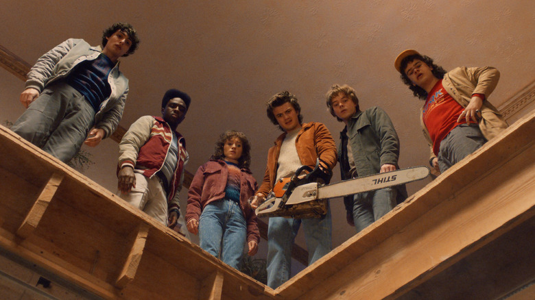Mike, Lucas, Nancy, Steve, Jonathan, and Dustin looking down (with Steve holding a chainsaw) in Stranger Things season 5