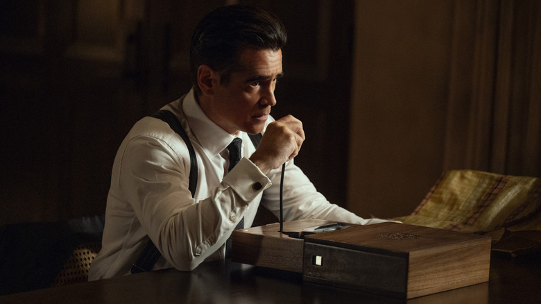 Colin Farrell as John Sugar sitting at a desk and holding an old CB radio in his hand in Sugar