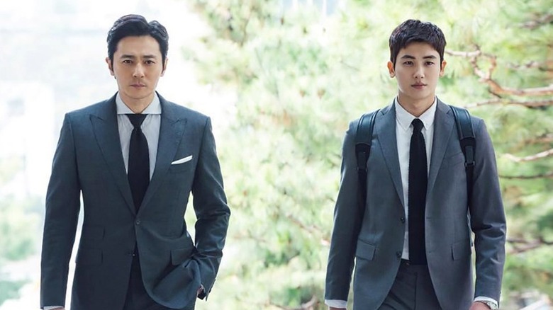Go Yeon-woo (Park Hyung-sik) and Choi Kang-seok (Jang Dong-gun) walk together by some trees in Suits