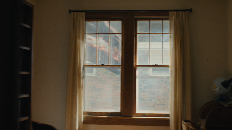 A dinosaur walking by the window in The End of Oak Street