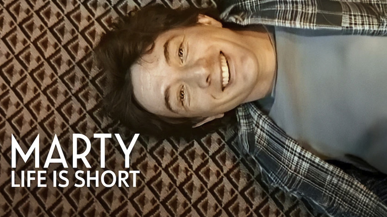 Martin Short laying sideways on a carpet