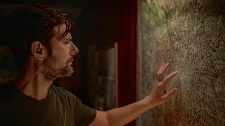Adam Scott studies a map on a wall in The Whisper Man