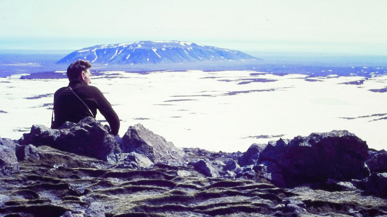 A man sits on a mountain, overlooking a glacier in Time and Water