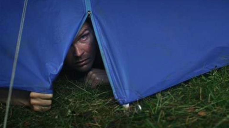 Man peeking under tent flap