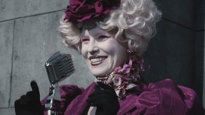 Effie Trinket at the microphone during the reaping in The Hunger Games