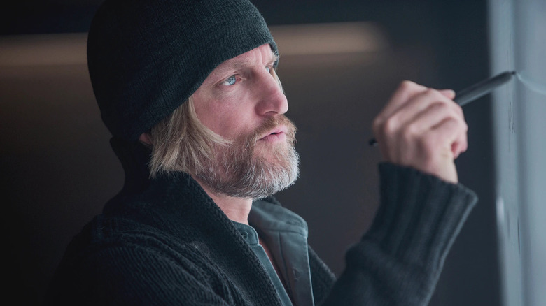 Haymitch in a black cap writing on a whiteboard in The Hunger Games: Mockingjay - Part 1