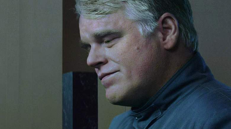 Plutarch in District 13 clothes looking down in The Hunger Games: Mockingjay