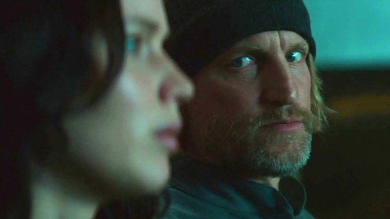 Haymitch in a black cap looking over at Katniss in the Mockingjay movies