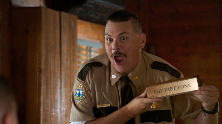 Kevin Heffernan como Farva segurando sua placa de Fart Zone em Super Troopers 2