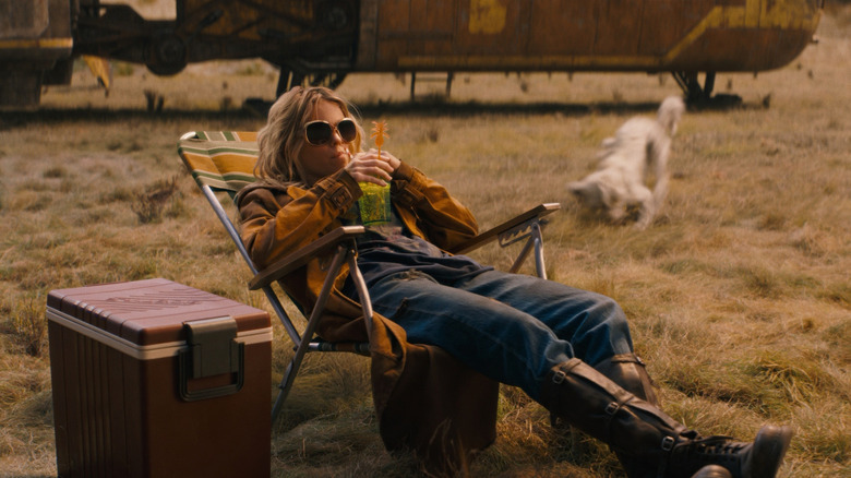 Milly Alcock as Supergirl sitting on a lawn chair with a drink in Supergirl