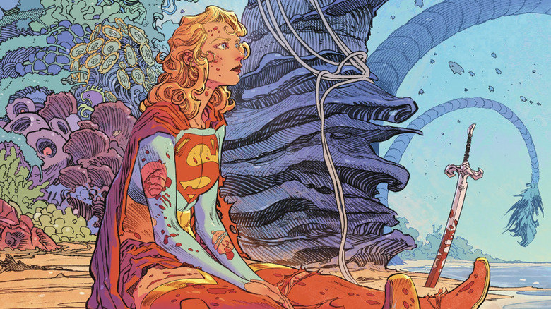 Supergirl sat on a beach looking up covered in blood