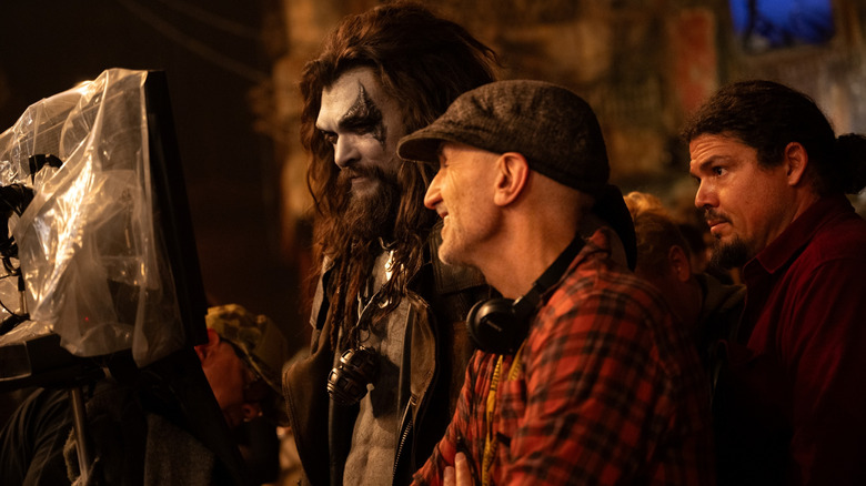 Jason Momoa in full costume and makeup as Lobo standing next to director Craig Gillespie and looking at a monitor on the set of Supergirl