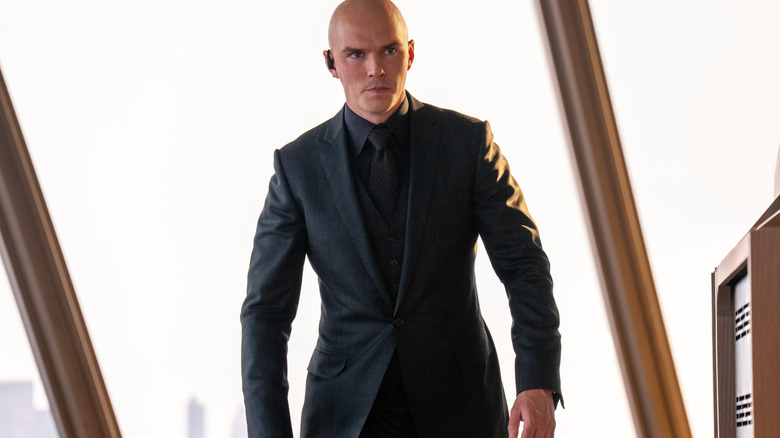 Nicholas Hoult as Lex Luthor wearing a suit and earpiece with a serious expression on his face in Superman