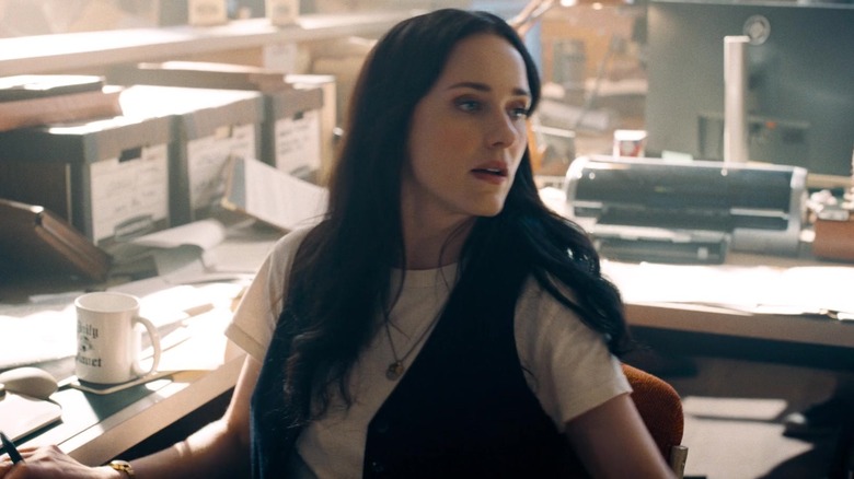 Rachel Brosnahan as Lois Lane sitting at her desk in Superman