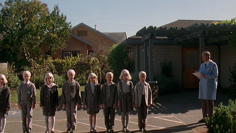 A line of eerie children next to a doctor in Village of the Damned