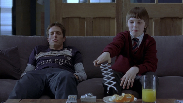 Will Freeman (Hugh Grant) sitting on the sofa with (Marcus Brewer) Nicholas Hoult in About a Boy