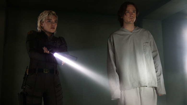 Yelena Belova (Florence Pugh) stands with a gun and a flashlight next to an unarmed Bob (Bill Pullman) in Thunderbolts