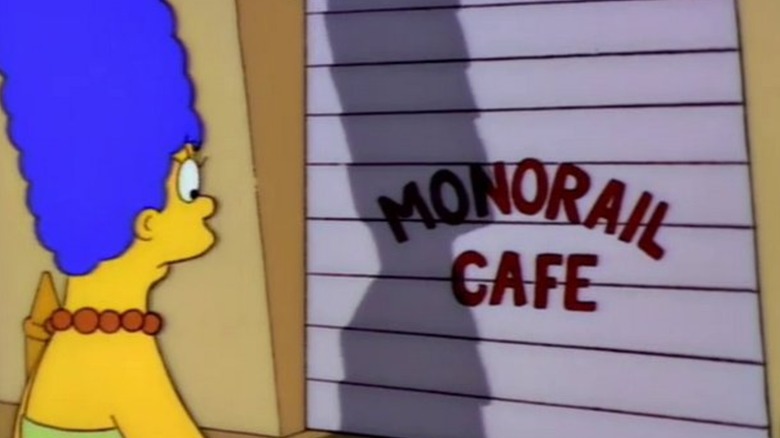 Marge looks at a closed shop labeled Monorail Cafe in Simpsons